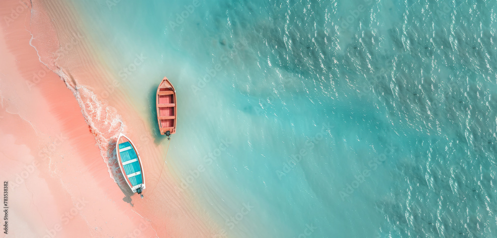 A stunning aerial summer shot capturing two boats on the shore, where the turquoise sea meets the pink sandy beach