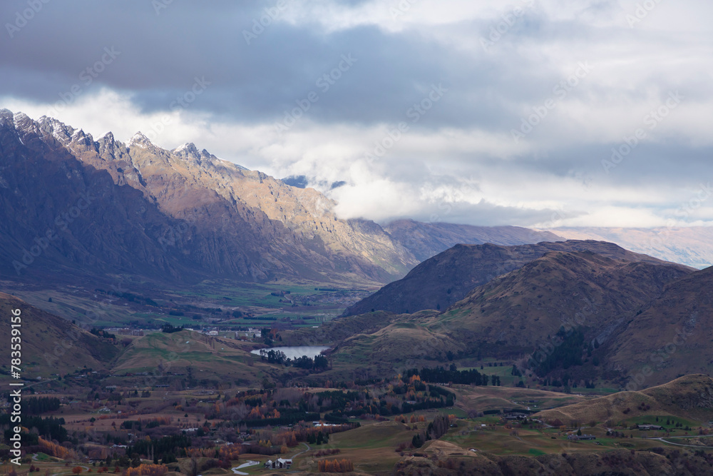 Photograph from Coronet Peak of a mountain range and a large agricultural valley on a cloudy day in Queenstown on the South Island of New Zealand