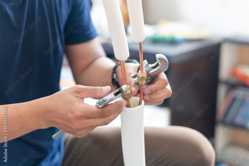 Technician man using a wrench to fix and joints copper pipe in air conditioner system, repair service and install new air conditioning concepts