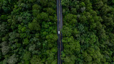 Aerial view electric vehicle car or EV car on green forest road, EV car travel in green season, Asphalt road and green forest, Forest road going through forest with electric car.