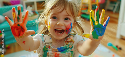 Happy little girl with colorful paint on her hands posing in the living room  playing and having fun at home