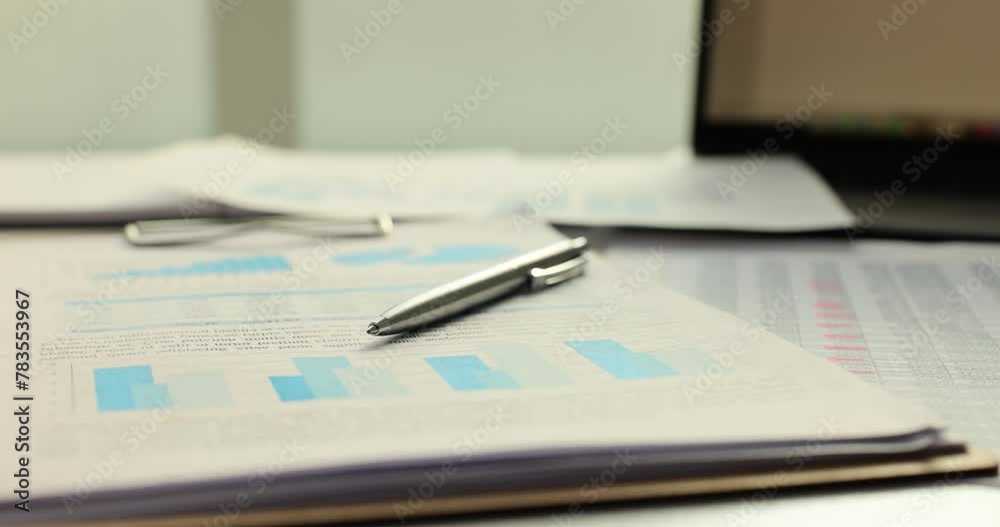 Pen and financial documents and charts on table Pen and financial documents and charts on table