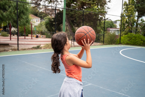 Latina school girl playing basketball at park