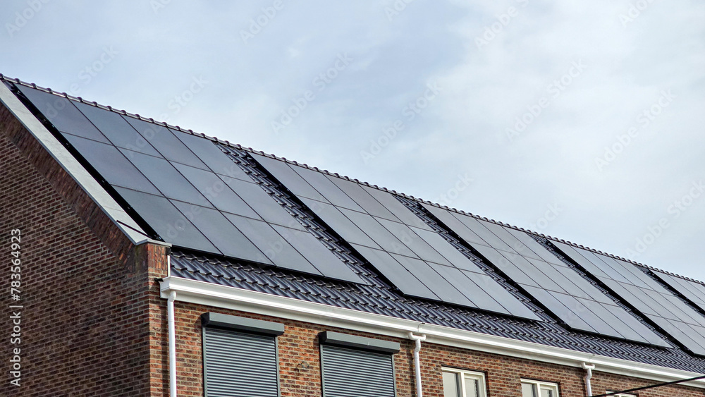 street of Newly built houses with black solar panels on the roof against a sunny sky Close up of new building with black solar panels. Zonnepanelen, Zonne energie, Translation: Solar panel, Sun Energy