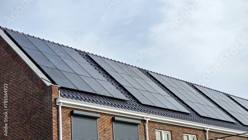 street of Newly built houses with black solar panels on the roof against a sunny sky Close up of new building with black solar panels. Zonnepanelen, Zonne energie, Translation: Solar panel, Sun Energy