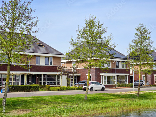 Newly built houses with black solar panels on the roof against a blue sky Close up of new family homes with black solar panels. Zonnepanelen, Zonne energie, Translation: Solar panel, Sun Energy photo