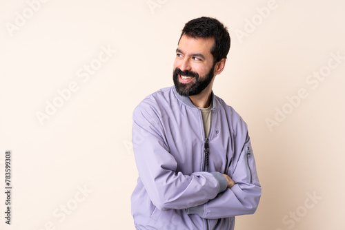 Caucasian man with beard wearing a jacket over isolated background looking to the side and smiling