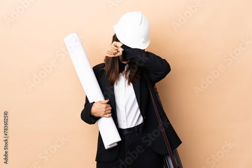 Young architect woman holding blueprints over isolated background covering eyes by hands