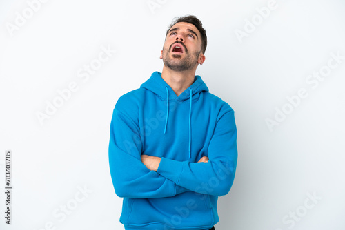 Young caucasian man isolated on white background looking up and with surprised expression