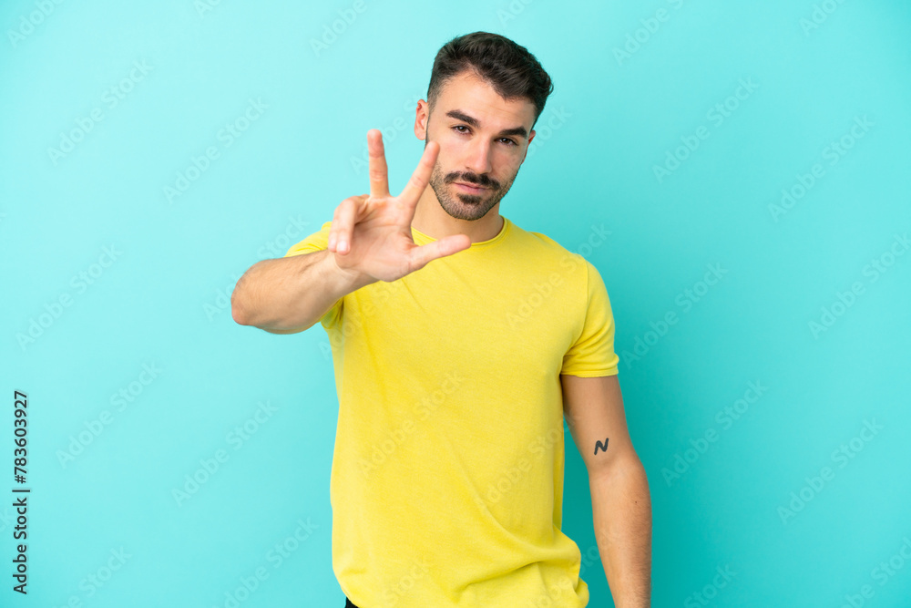 Fototapeta premium Young caucasian man isolated on blue background happy and counting three with fingers