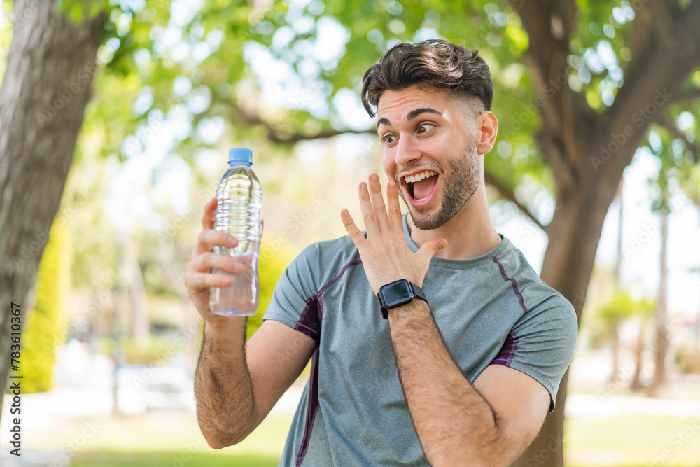 Young handsome sport man with a bottle of water at outdoors with surprise and shocked facial expression Young handsome sport man with a bottle of water at outdoors with surprise and shocked facial expression