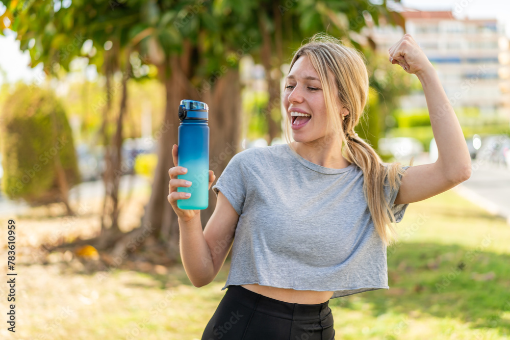 Young blonde sport woman with a bottle of water at outdoors celebrating a victory Young blonde sport woman with a bottle of water at outdoors celebrating a victory