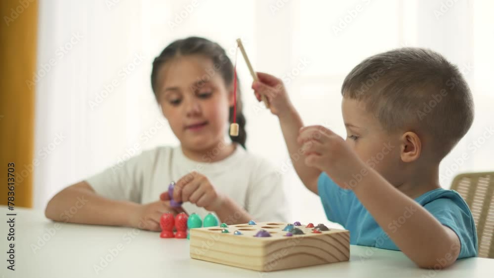 Children sit at table in kindergarten. Boy and girl play toys in kindergarten. Preschool education at home. Educational games in kindergarten. Happy children play toys in playroom.Cheerful active kids Children sit at table in kindergarten. Boy and girl play toys in kindergarten. Preschool education at home. Educational games in kindergarten. Happy children play toys in playroom.Cheerful active kids