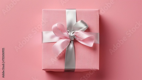a pink gift box adorned with a silver ribbon, set against a soft pastel pink background, showcasing a minimalist concept in a flat lay view.