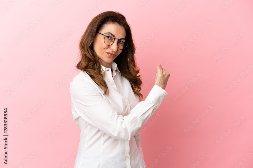 Middle aged caucasian woman isolated on pink background doing strong gesture Middle aged caucasian woman isolated on pink background doing strong gesture