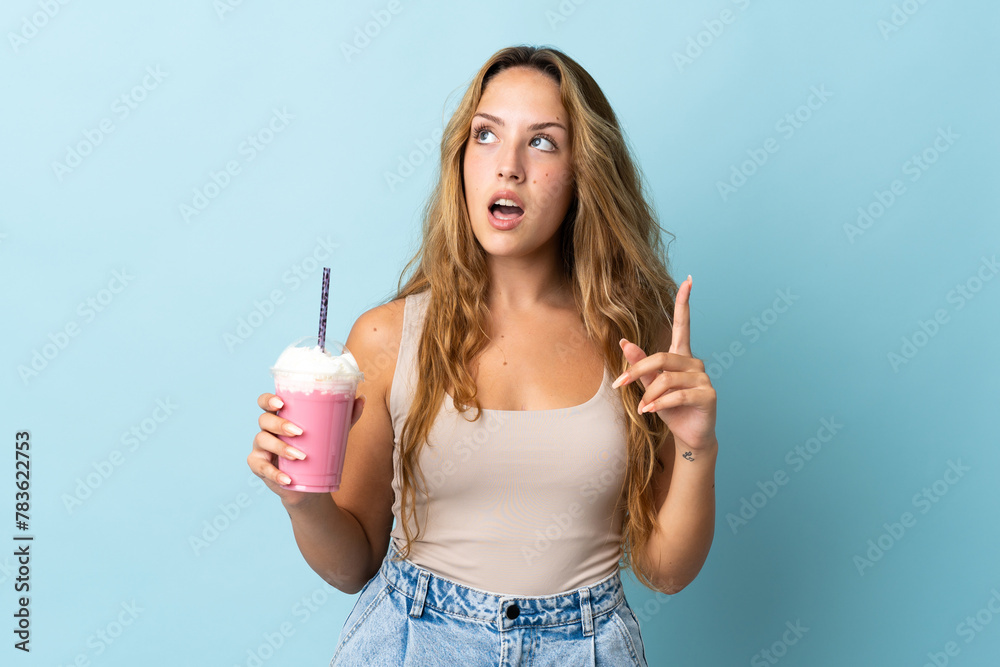 Young woman with strawberry milkshake isolated on blue background thinking an idea pointing the finger up Young woman with strawberry milkshake isolated on blue background thinking an idea pointing the finger up