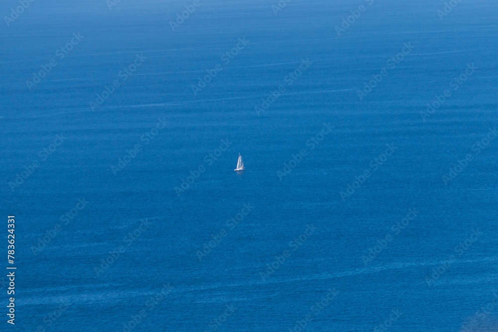 Aerial view of the lonely boat in the middle of the blue calm ocean