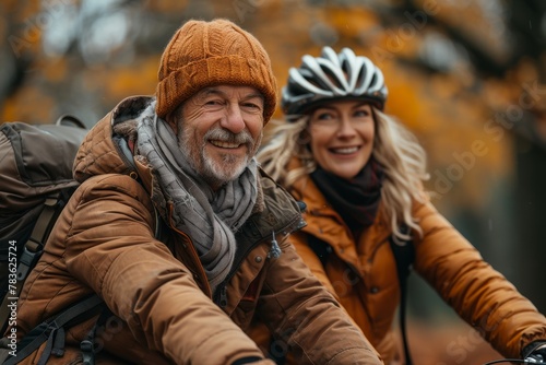 Smiling older couple biking together, dressed in warm autumn clothing