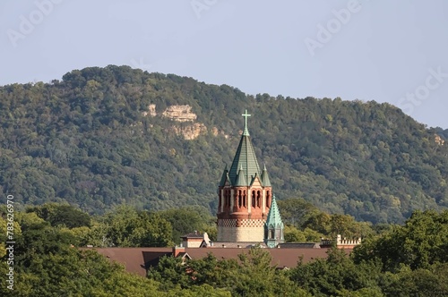 Church steeple surrounded by nature with a hill in the background