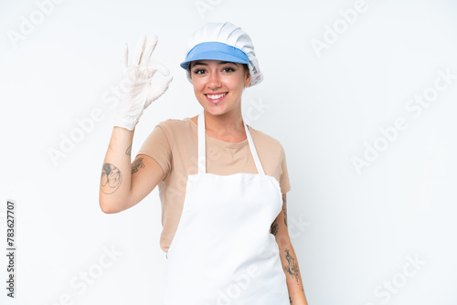 Fishmonger wearing an apron and holding a raw fish isolated on white background showing ok sign with fingers