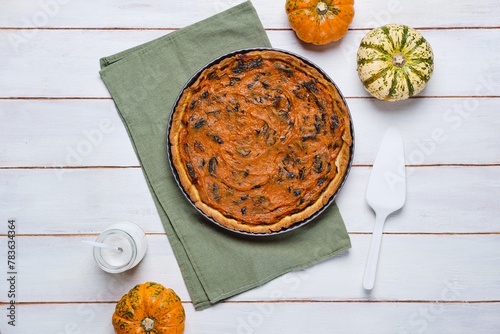 Round tart with pumpkin and prunes in the form for baking on a light derving background. Pumpkin recipes. French cuisine. photo