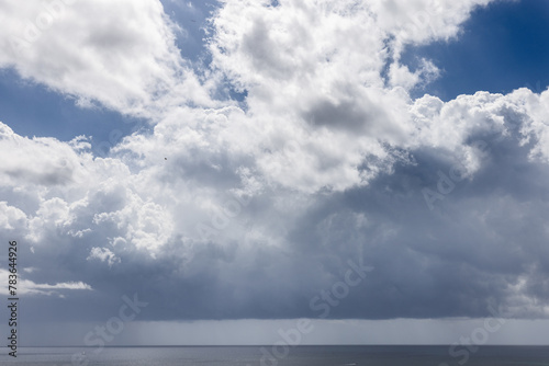 A dramatic view of the Ibiza seascape under a dynamic sky, where billowing clouds hint at an impending storm over the calm Mediterranean Sea