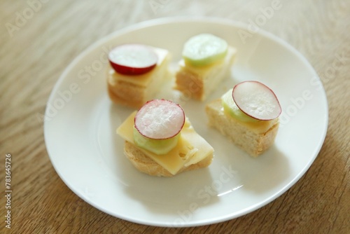 Closeup of mini sandwiches with cheese and radish on a white plate