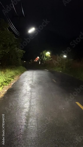 Evaporating moisture on a curvy road after a nocturnal downpour, with dimly lit surroundings