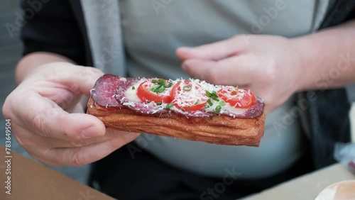Male hands holds a sandwich with sausage, cheese and tomato.