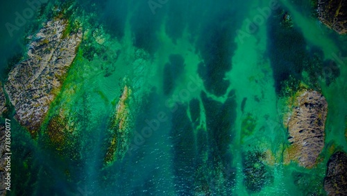 Aerial top view of a turquoise ocean with rocks