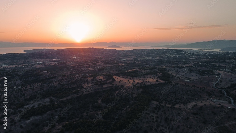 Bird's eye view of a green island against the sea at sunset Bird's eye view of a green island against the sea at sunset