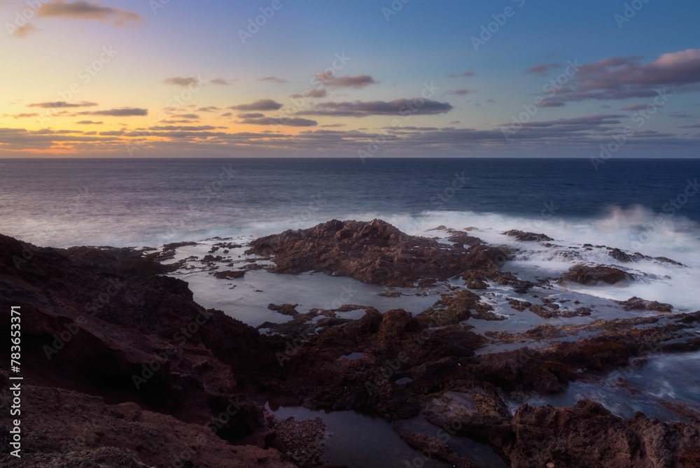 Beautiful view of ocean waves in a rocky beach during sunset