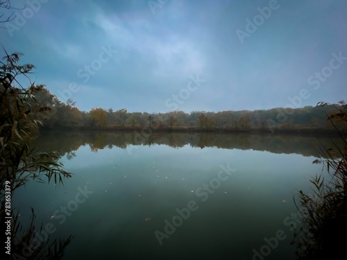 Scenic view of a calm lake with a reflection on trees and sunset sky on the surface