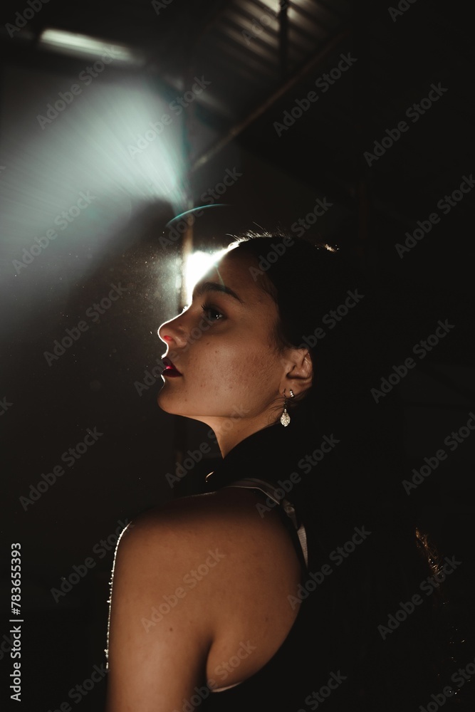 Vertical shot of a young caucasian woman against a spotlight