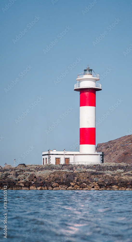 Vertical shot of red and white lighthouse from the sea