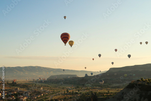 Colorful hot air balloons flying over the landscape of the Red Valley, Rose Valley, close to Goreme, Cavusin, Cappadocia, Turkey © anja