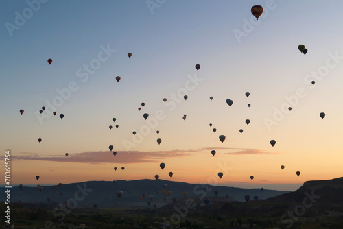 Dozens of hot air balloons rising over the landscape of the Red Valley, Rose Valley before sunrise, close to Goreme, Cavusin, Cappadocia, Turkey