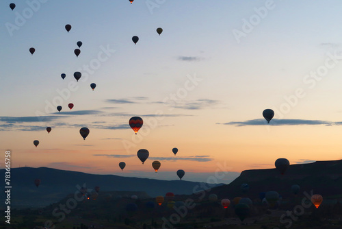 Many hot air balloons rising over the landscape of the Red Valley, Rose Valley before sunrise, close to Goreme, Cavusin, Cappadocia, Turkey photo