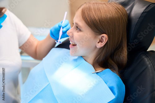 Smiling teenage girl communicates with a dentist in the office