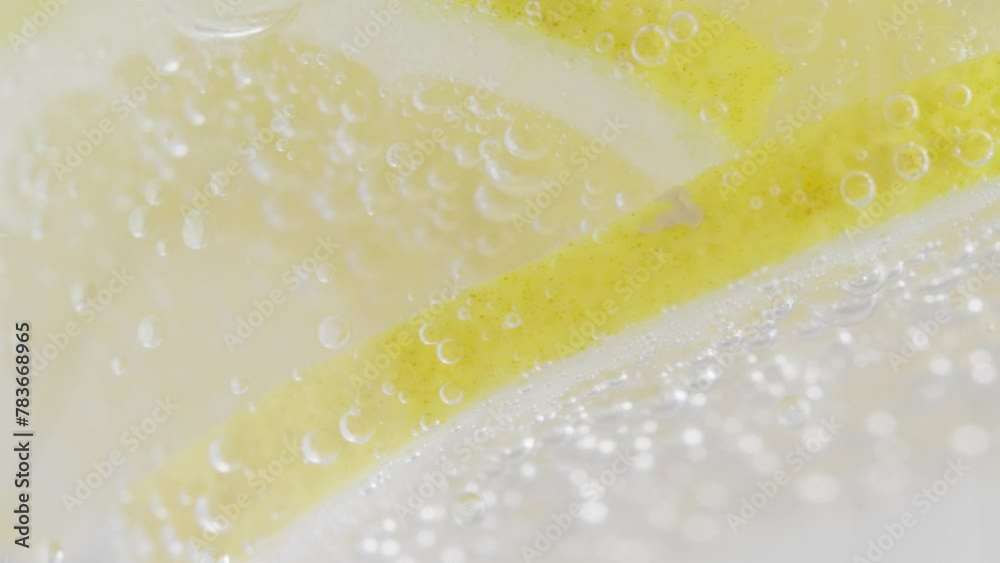 Macro shot capturing the effervescence of sparkling water with lemon slices and soda bubbles.