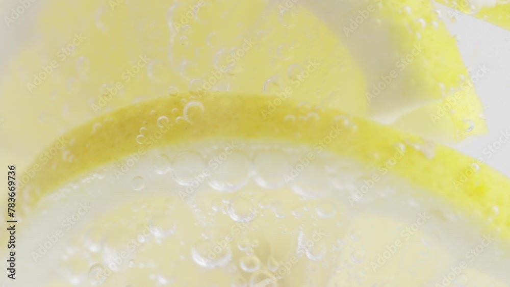Macro shot capturing the effervescence of sparkling water with lemon slices and soda bubbles.