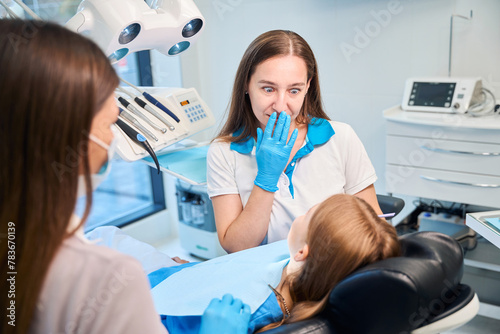 Dental hygienist and assistant are conducting appointment in dental office