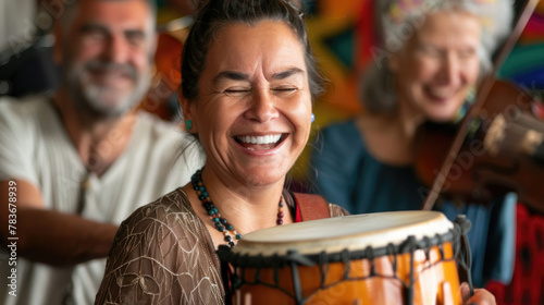 A woman joyfully plays a drum, smiling as she rhythmically strikes the drumhead with drumsticks photo