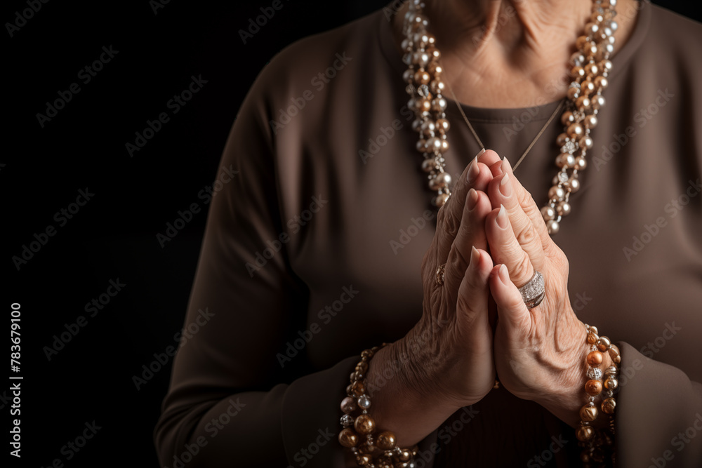 Mature woman's hands in prayer position with black background and copy space