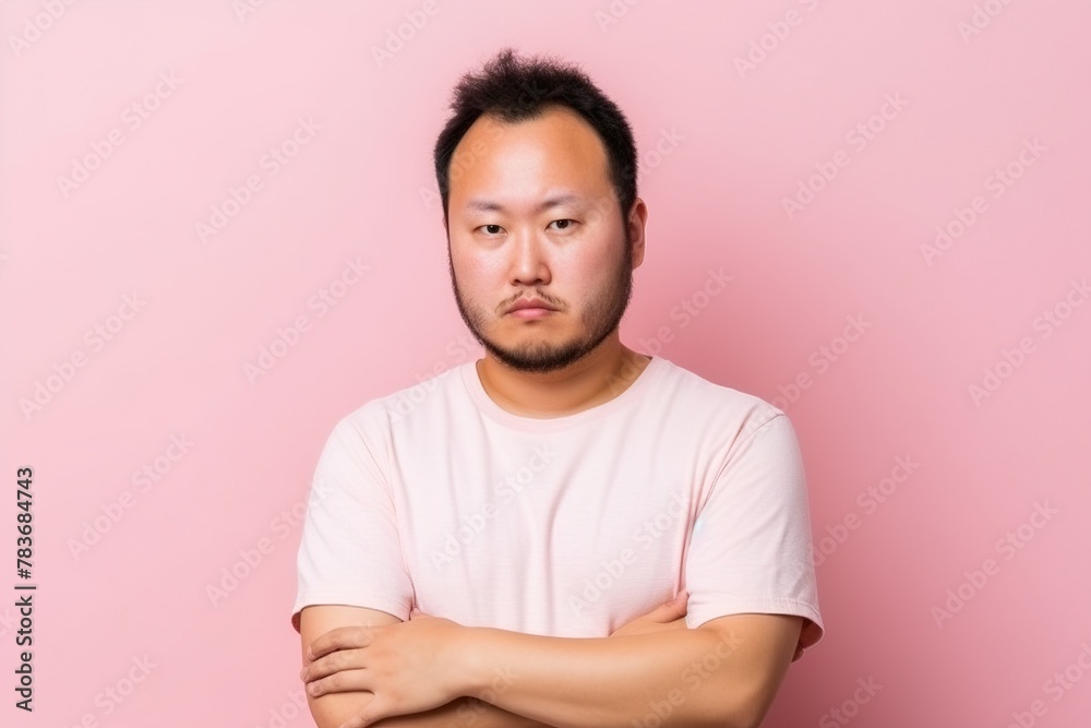 A man with a beard and a pink shirt is standing with his arms crossed A man with a beard and a pink shirt is standing with his arms crossed