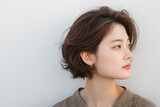 Profile view of a thoughtful asian woman with short hair against a white wall