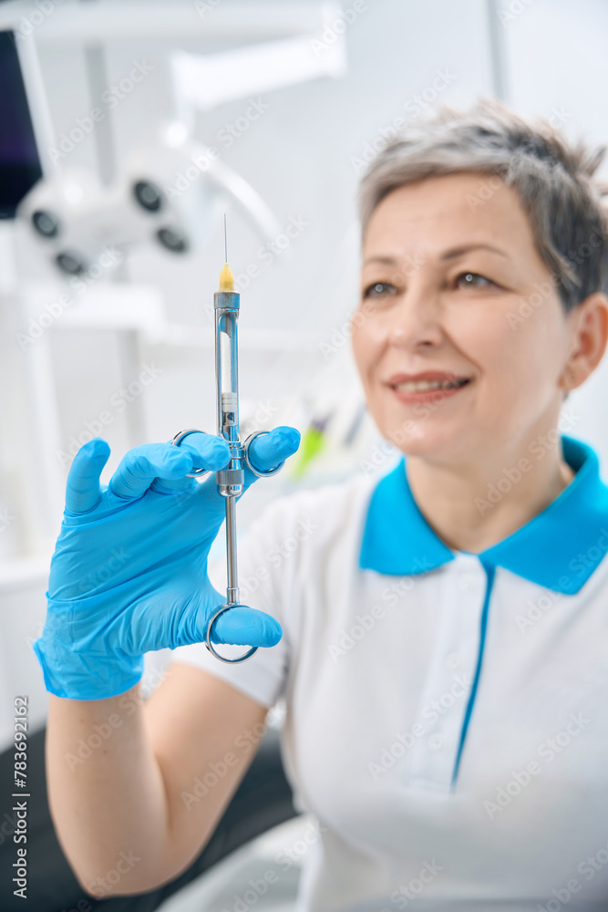 Nurse of dental therapist holding glass syringe with anesthetic inside Nurse of dental therapist holding glass syringe with anesthetic inside