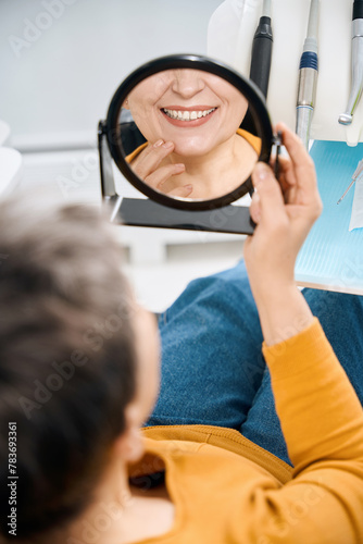 Mature woman looking at mirror with toothy smile