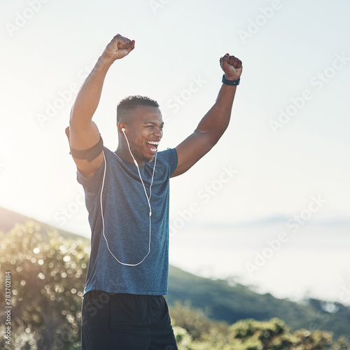 Victory, fitness and black man in nature, outdoor and earphones for exercise, training and workout. Summer, winner and athlete on hill, excited and sport for person, healthy and muscle in weekend