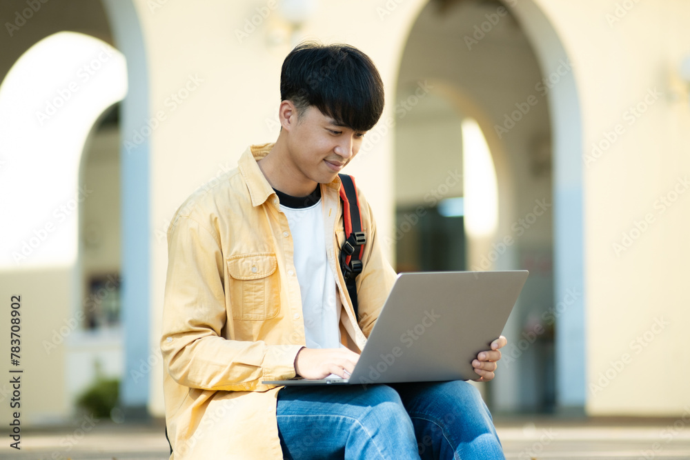 Pensive Student with Laptop Outdoors on University Grounds Pensive Student with Laptop Outdoors on University Grounds